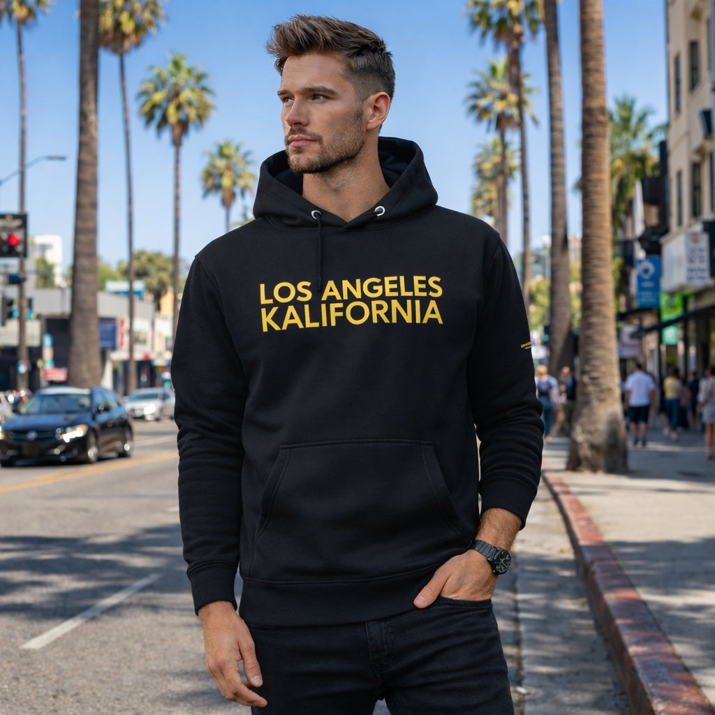 Man wearing a black hoodie with 'Los Angeles Kalifornia' text on a city street with palm trees.